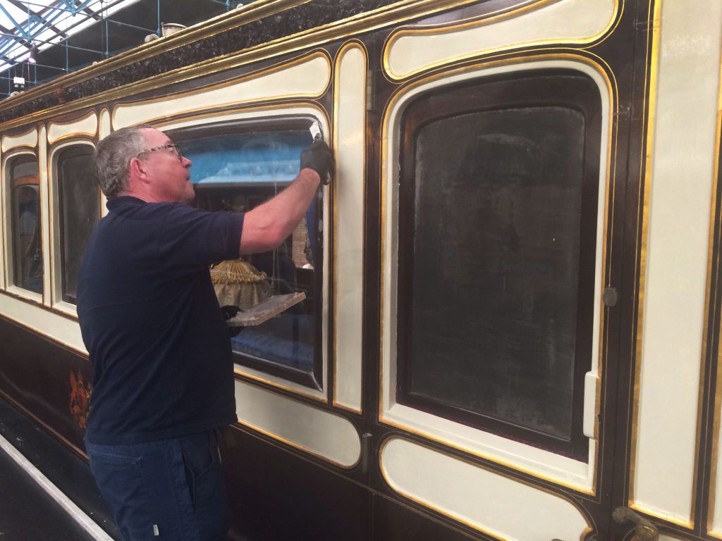 Conservation assistant Chris Binks applying filler to the window frames of Queen Victoria's carriage.