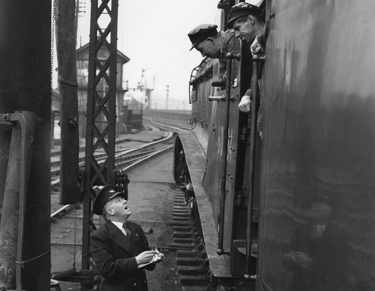 Driver Bill Hoole and his fireman lean from the cab of 'Lord Faringdon' to chat with station guard, c1956. 