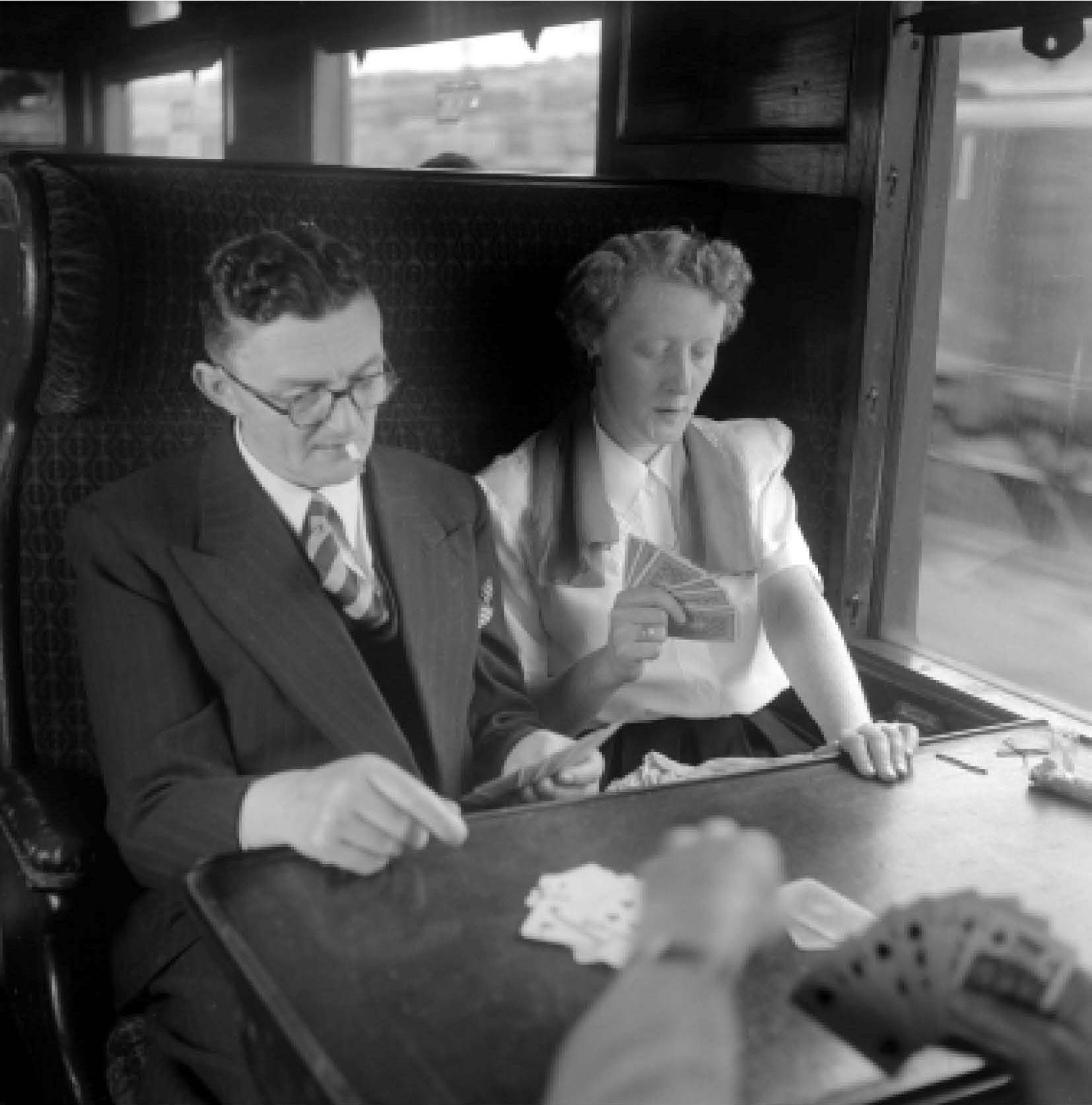 man and a woman playing cards on a train