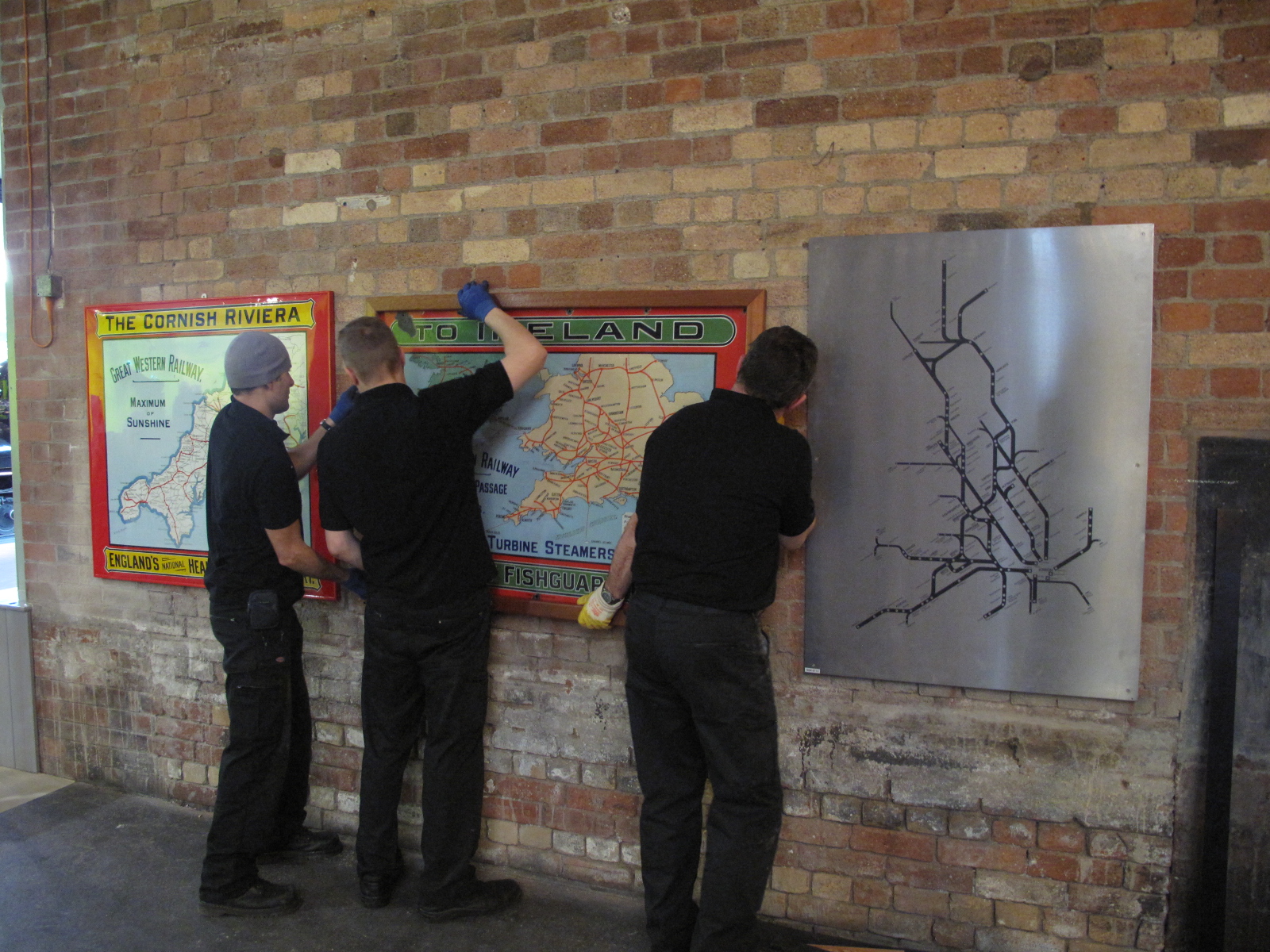 Our Conservation team have been installing collection items throughout Station Hall. Here they're adding some railway maps to the Concourse wall.