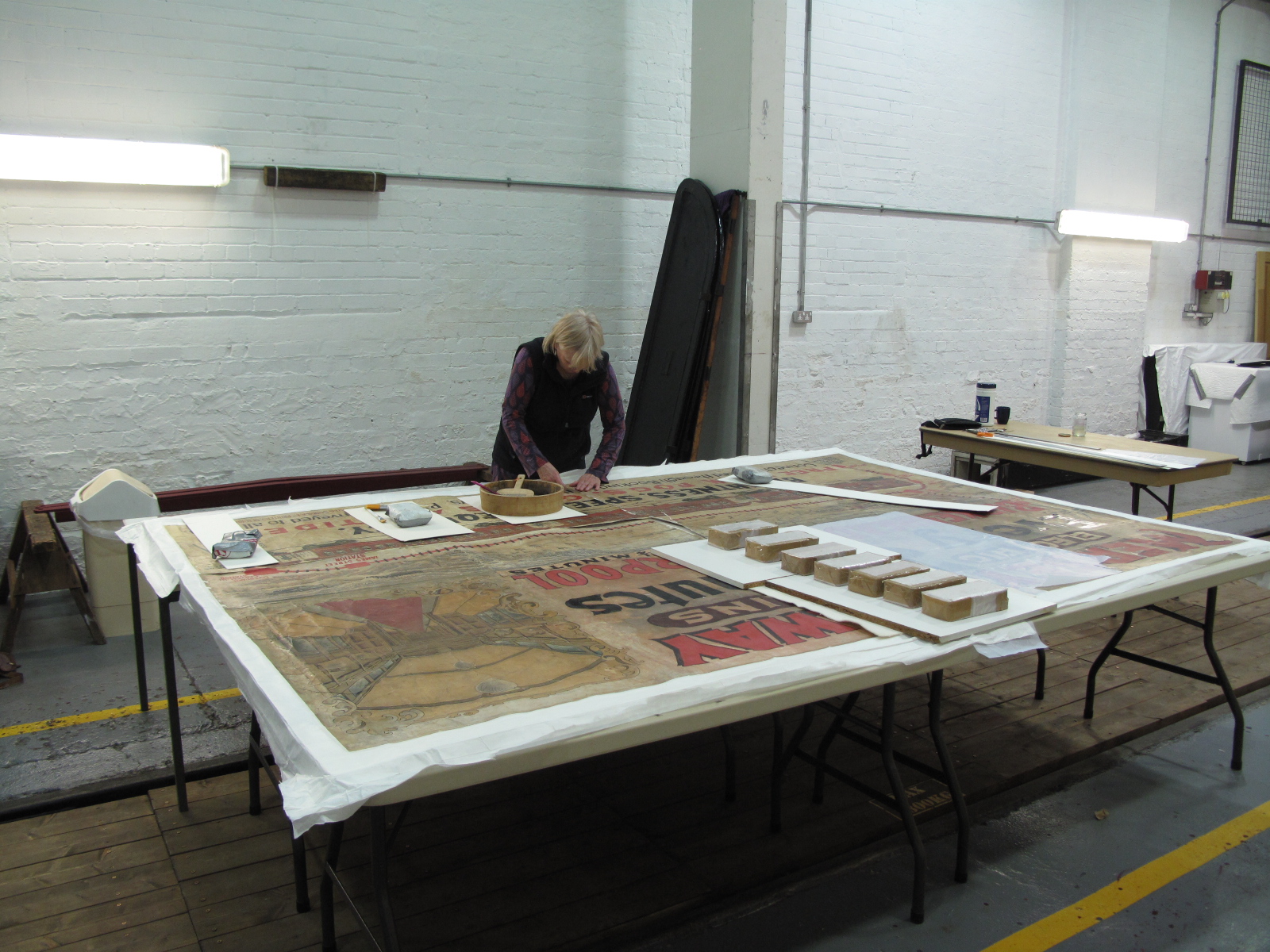 The poster was made up of smaller individual sheets of paper much like a modern billboard. Here conservator Ruth rejoins the last of the sections.