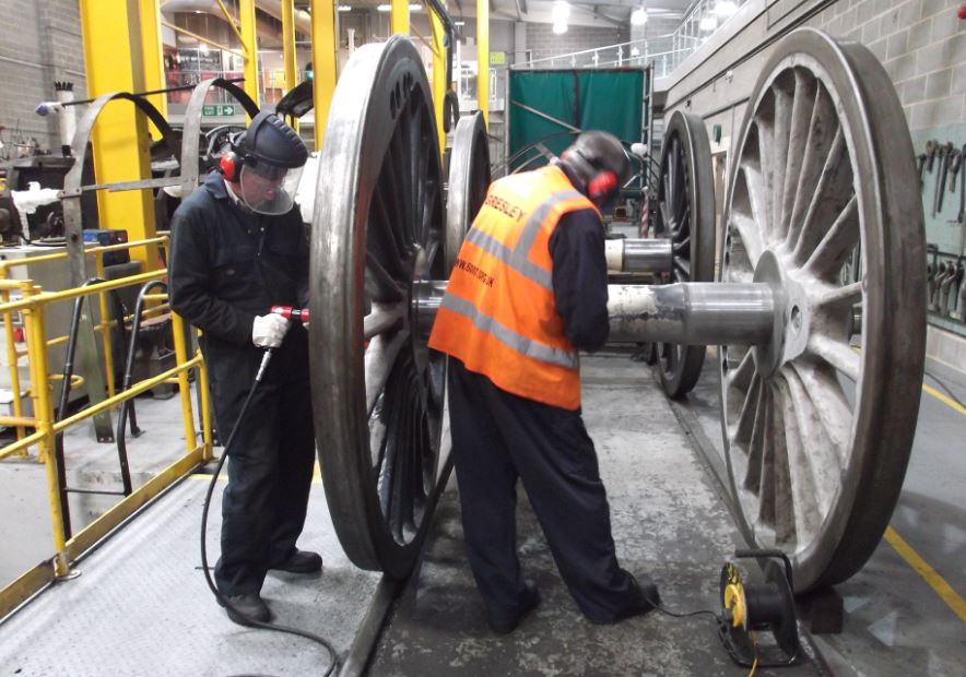 Malcolm Bateman and Malcolm Hutton removing paint from the leading coupled wheelset.