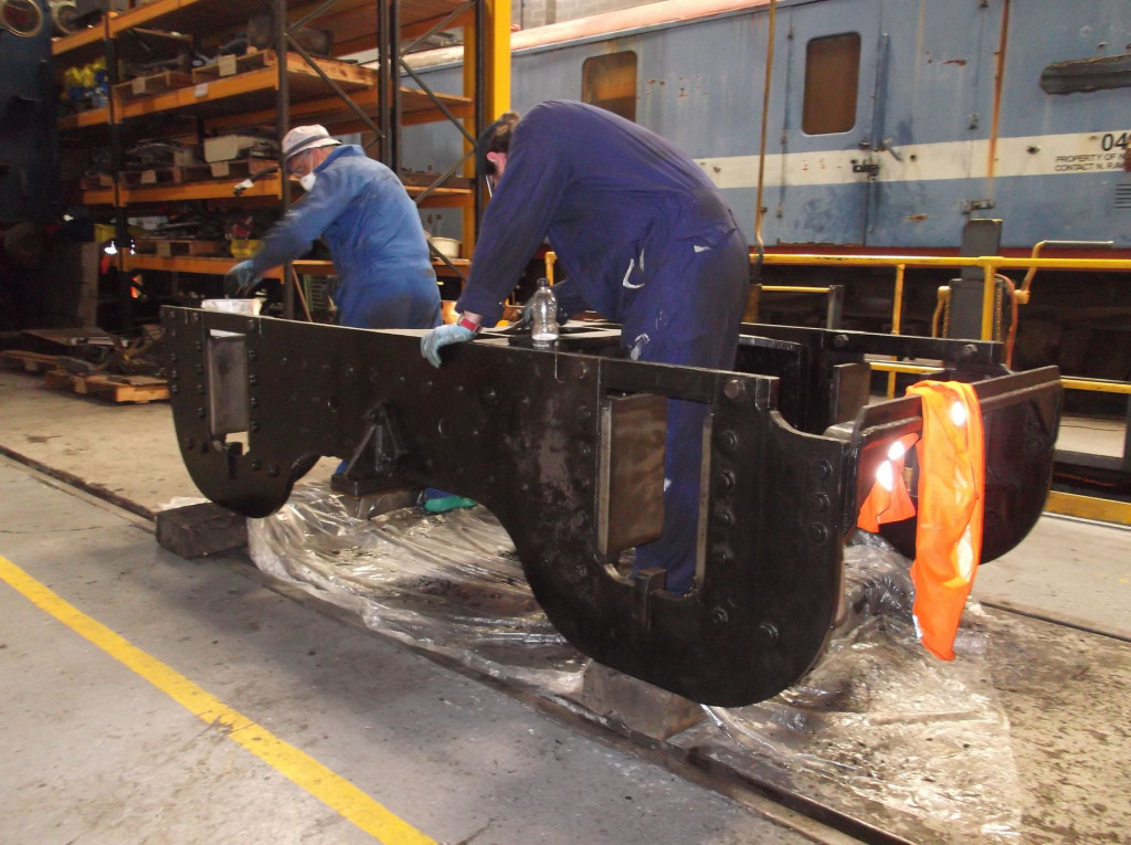 The upturned bogie frames being cleaned by Rod Thomas and Tom Bell.