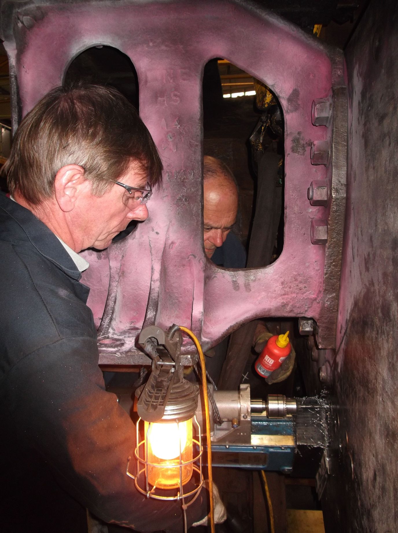 Malcolm Bateman operates the mag drill while drilling through life-expired rivets while Pete Brackstone applies lubricant. 