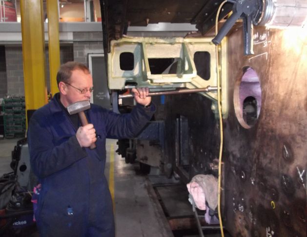 The first part fitted to the loco during this overhaul was a fitted bolt. Locomotive Engineer Darrin Crone starts the bolt in to its hole, before Chief Mechanical Engineer Richard Swales drives it home a year to the day since the loco entered the workshop.