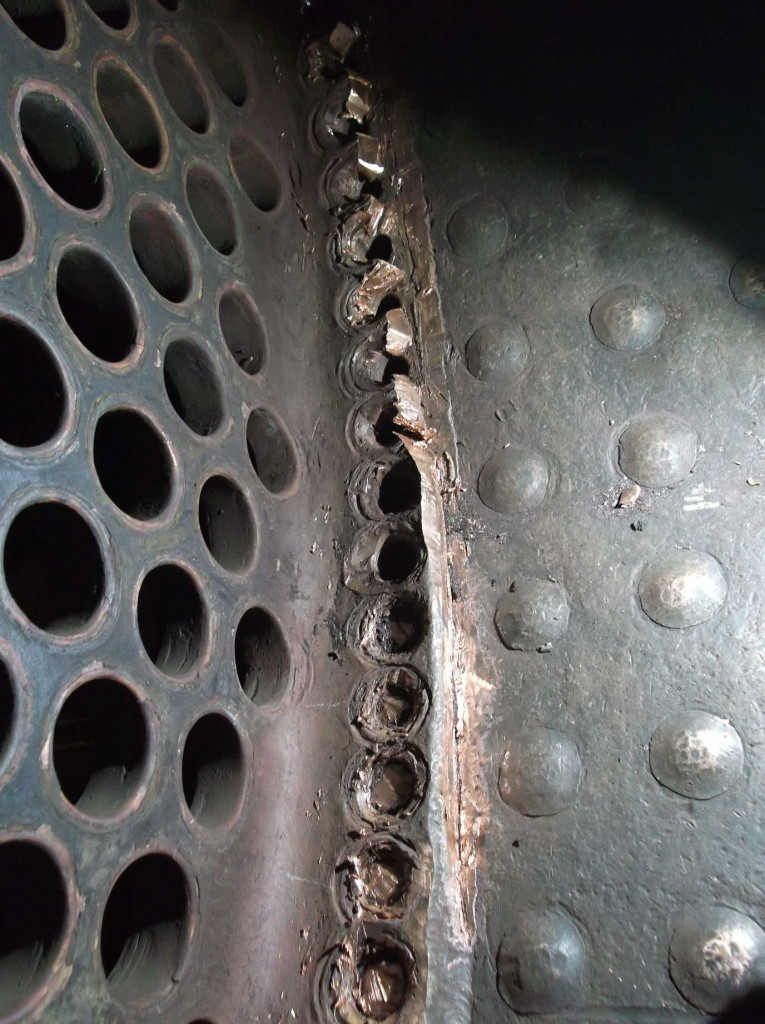 Work continues on the removal of the firebox tubeplate (left). The patch screw heads are removed and the sealing weld with the tubeplate edge to the patch screw. The patch screw is then removed. This careful removal is required to prevent damaging the combustion chamber copper plate below