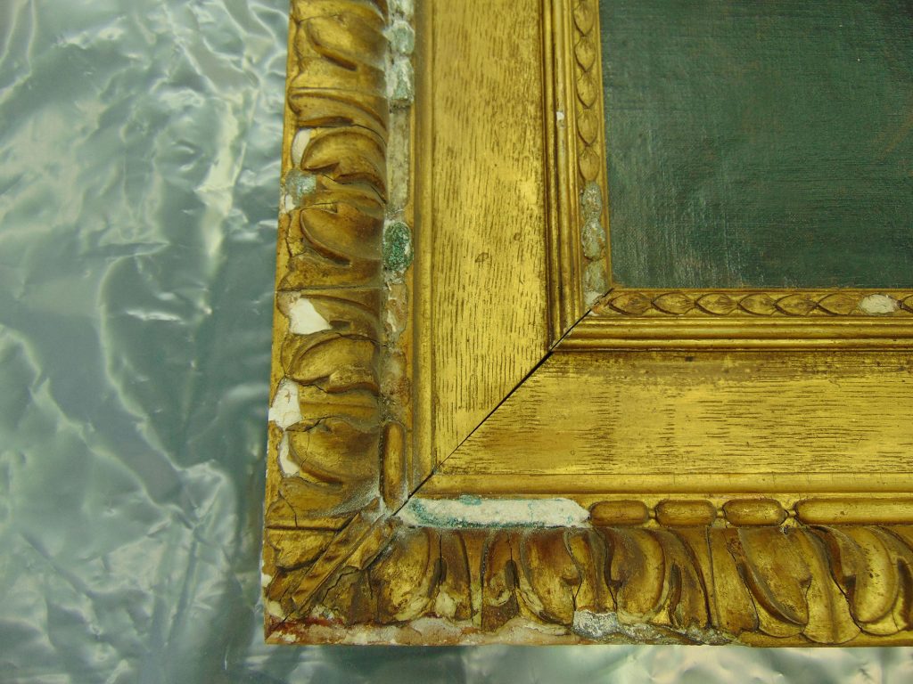 Corner of a damaged gilt picture frame on the conservation workshop bench