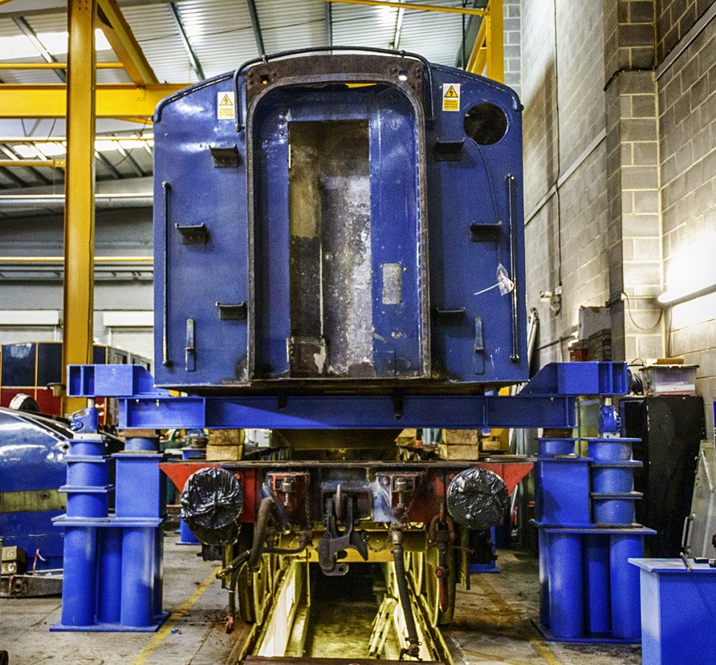 Locomotive tank lifted above the frames using bright blue lifting beams.