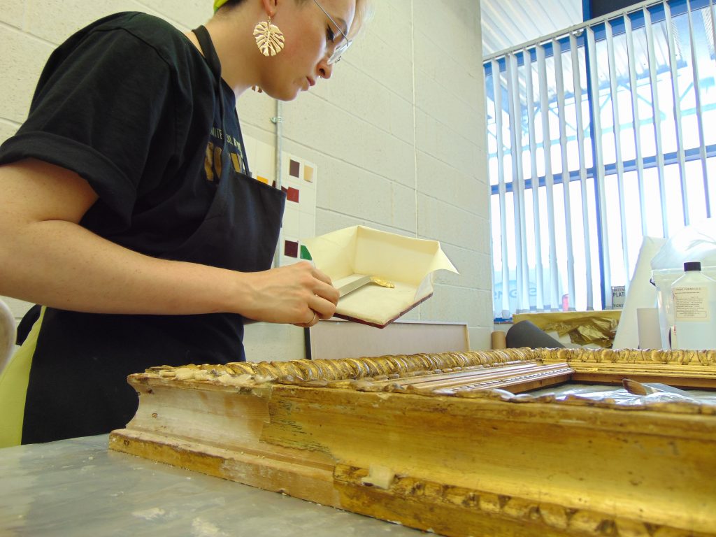 Conservator applying gold leaf to a picture frame