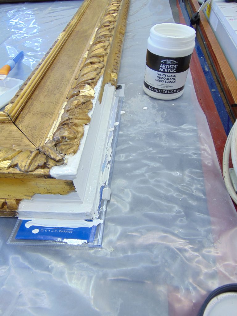 Corner of a gilt picture frame with a white layer of gesso newly applied