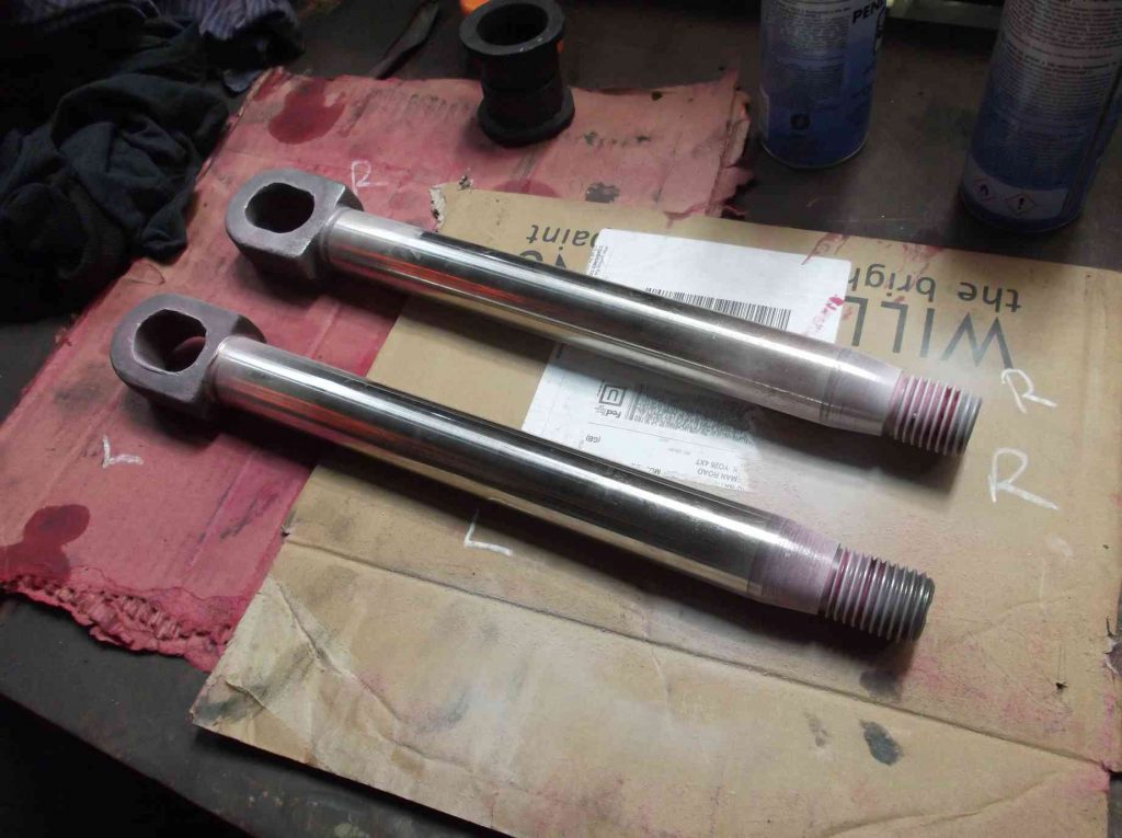 Two tender vacuum brake piston rods laid on cardboard, during inspection