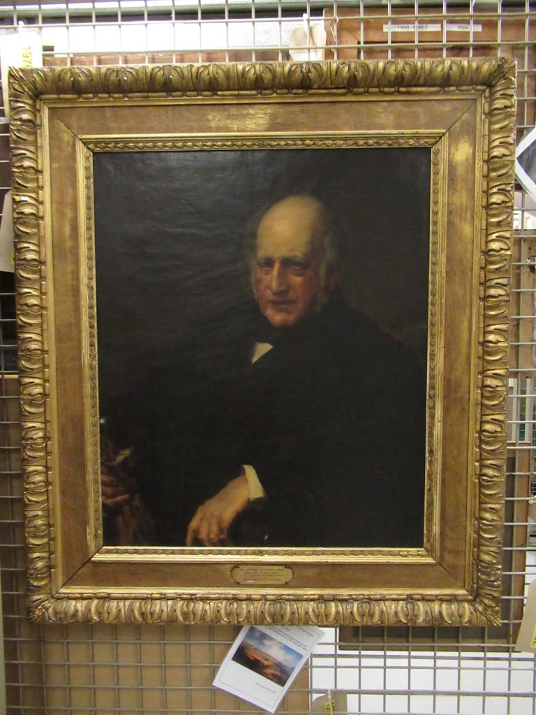 A painting in a gilt frame hanging on a rack in the art store.
