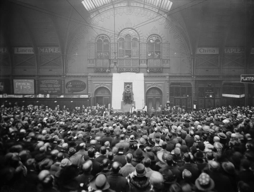 Crowd of people with Great Western Railway War Memorial behind at Paddington Station