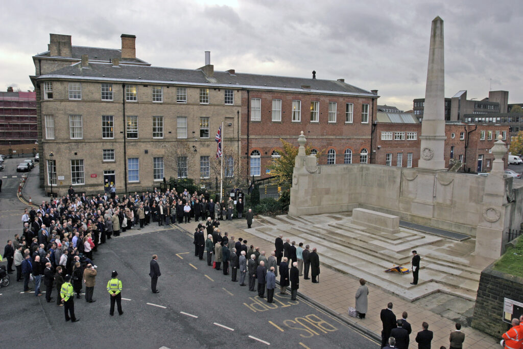 Photograph of the North Eastern Railway War Memorial, York, taken from the city walls, showing the memorial with obelisk and a crowd attending the commemoration of Rembrance Day in 2005