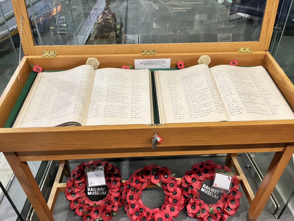 Display case containing roll of honour books, with wreaths underneath the case