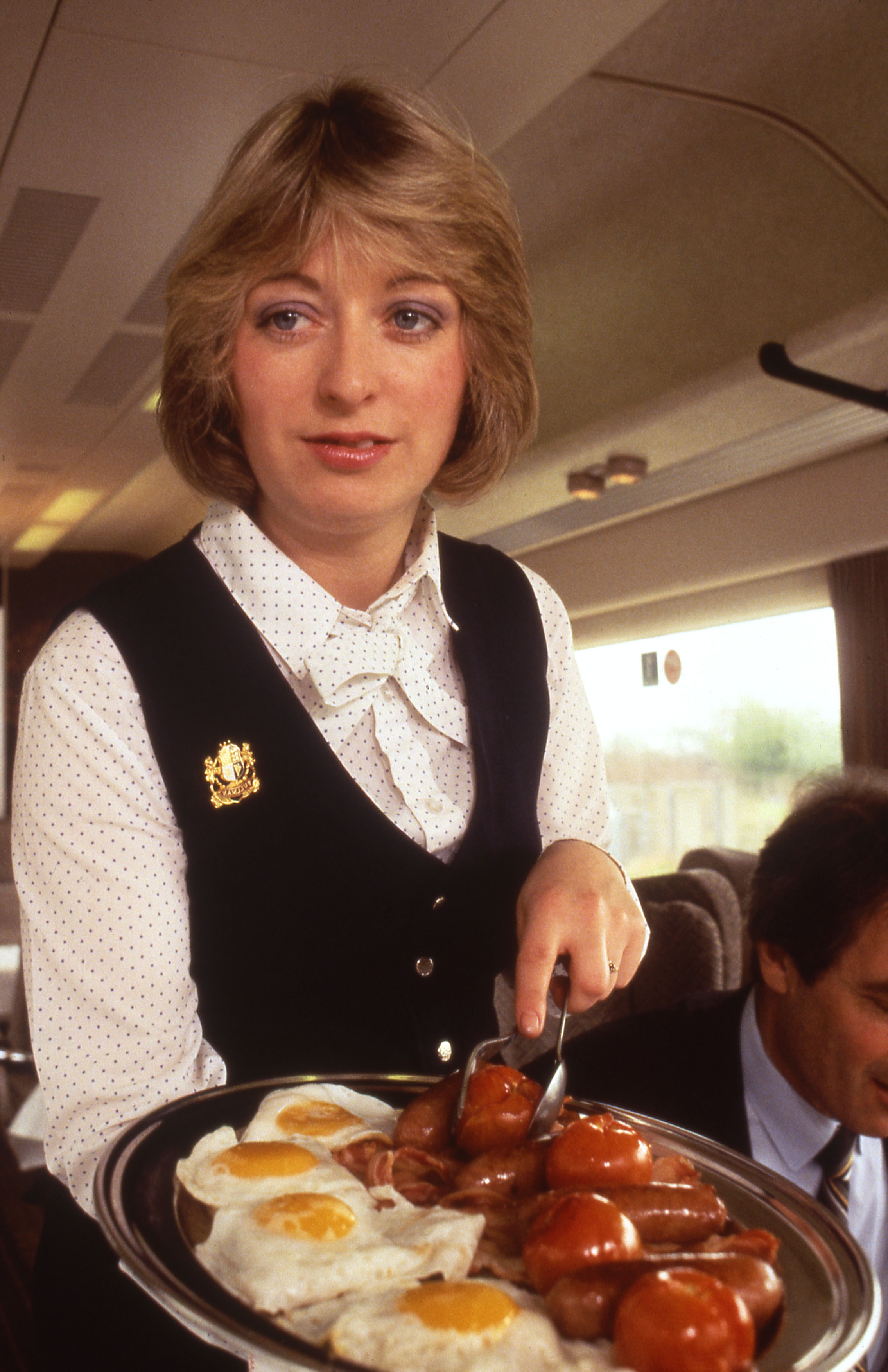 Pullman stewardness serving a breakfast platter, 1980s.