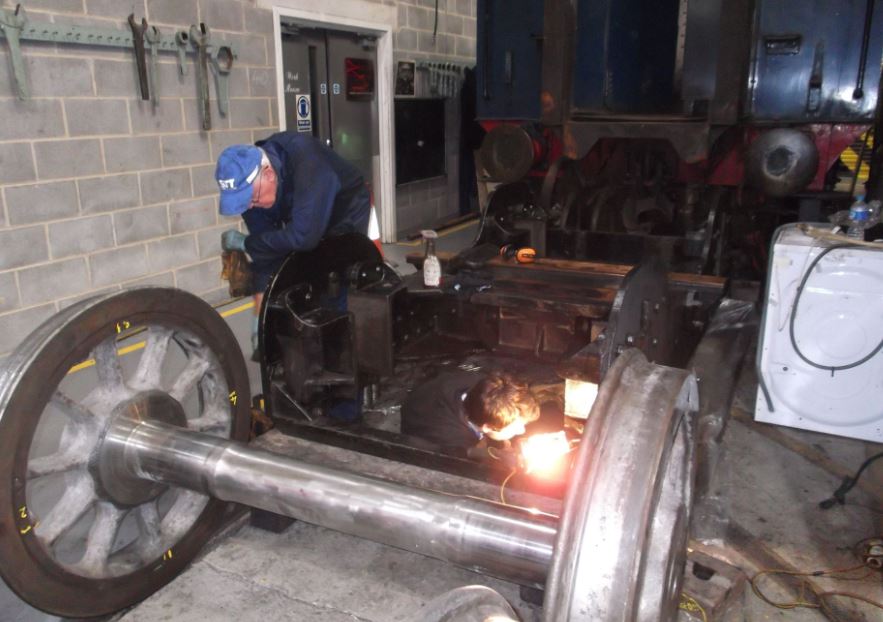 The bogie frames require thorough cleaning then all the paint removing for the frame material to be examined in detail. Alan Pitt is assisted by Philip Wilson.