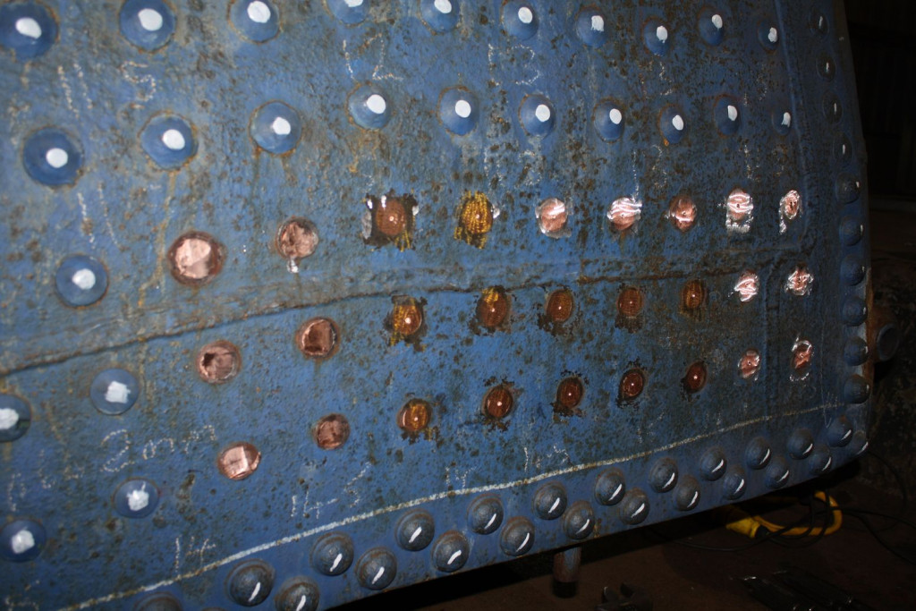 The heads of the boiler firebox stays on the left hand side of the outer wrapper are being removed at Llangollen.