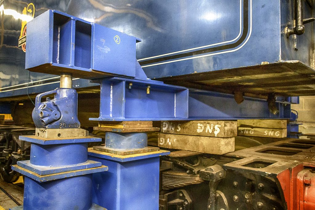 Locomotive tank lifted above the frames using bright blue lifting beams.