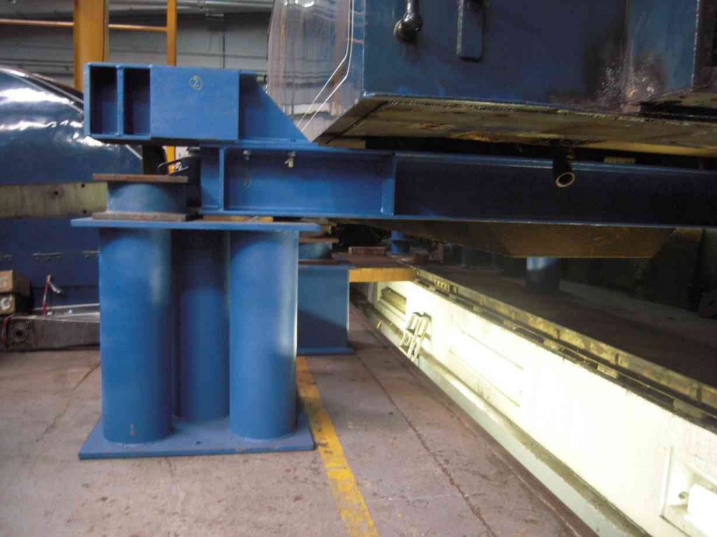 Locomotive tank sitting on bright blue lifting beams in the workshop.
