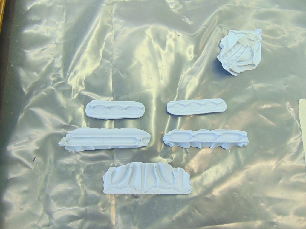 Six pieces of light-blue Steramould with impressions of the frame details, on a plastic sheet