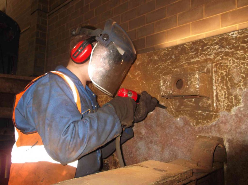 Needle-gunning the inside of the frame plates