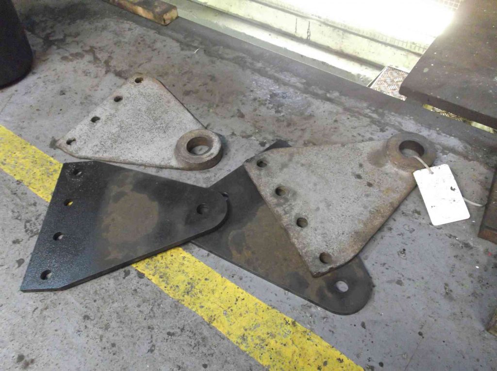 Four brake cylinder support brackets from locomotive Sir Nigel Gresley on the workshop floor.