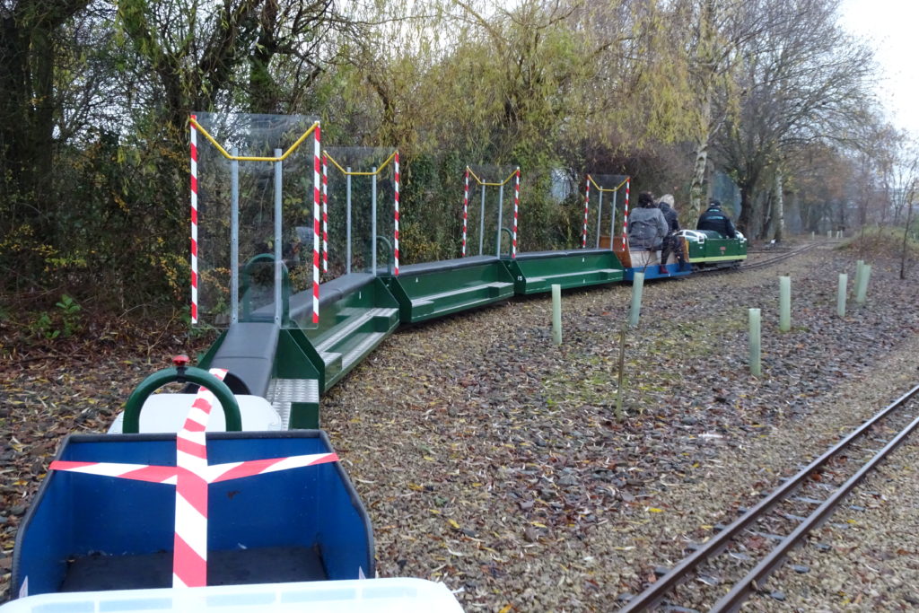 Miniature railway carriages on track, with clear plastic screens separating the seats