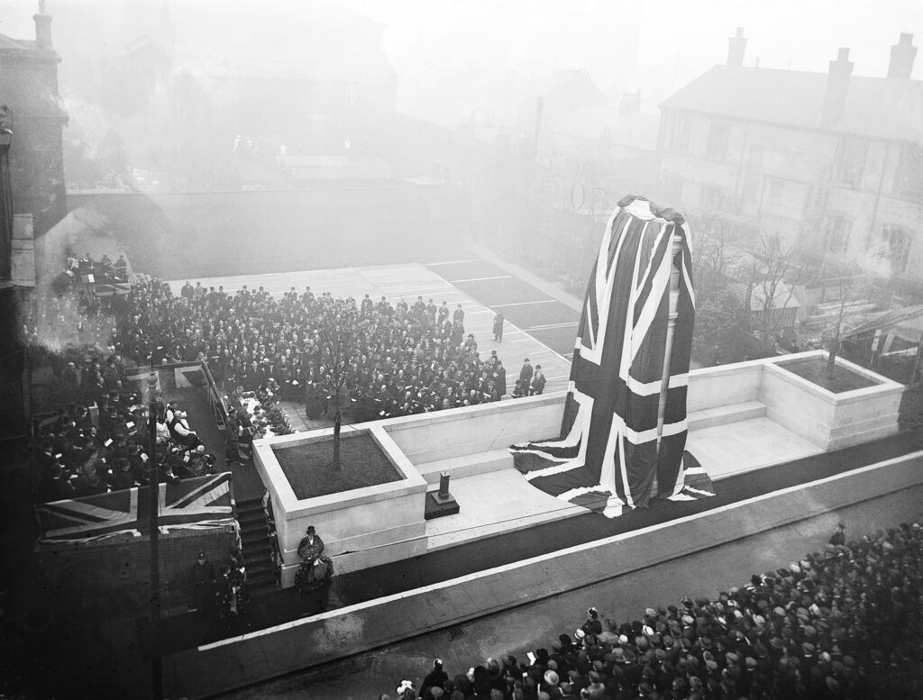 Railway War Memorial being unveiled at Derby, the cenotpah is covered with a Union Flag, surrounded by crowds of people attending the ceremony