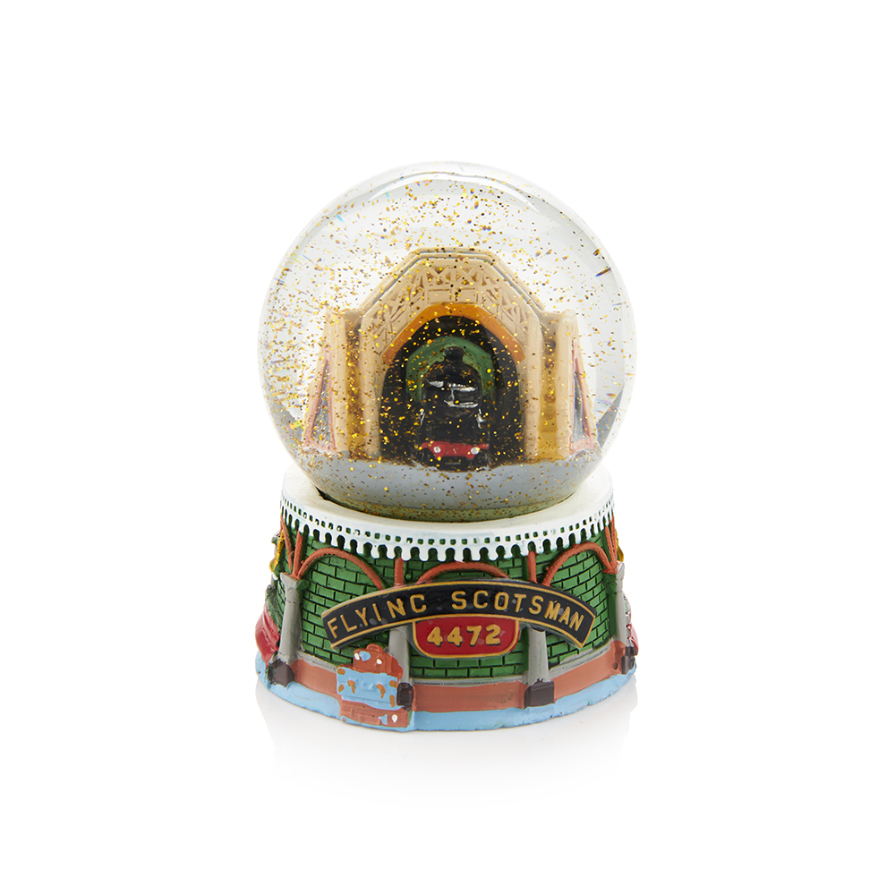 Glass snowgobe with gold snow inside falling on train inside a station arch