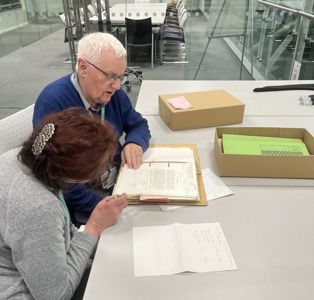 Two people sat at a desk looking at archive files