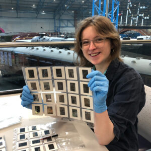 Esme with blue gloves on holding up some photo slides